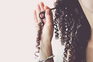 Woman holding a strand of long, coily hair